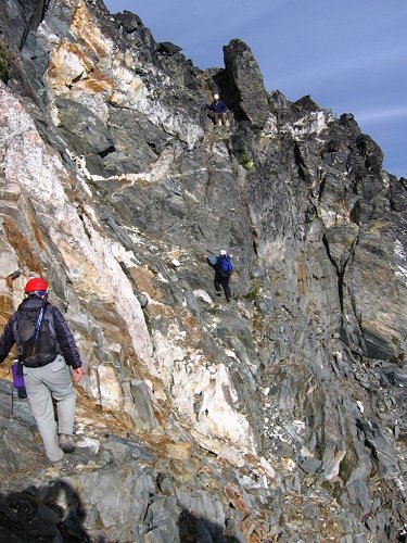 Here's the party traversing on the steep ledges below the crest.  
Eric is in the foreground, together with my shadow taking a picture.
Richard is in the final notch at top, wearing a white helment.
Eileen is in the center, preparing to scramble up and left into the corner, 
then follow the horizontal write line back right to get below Richard.